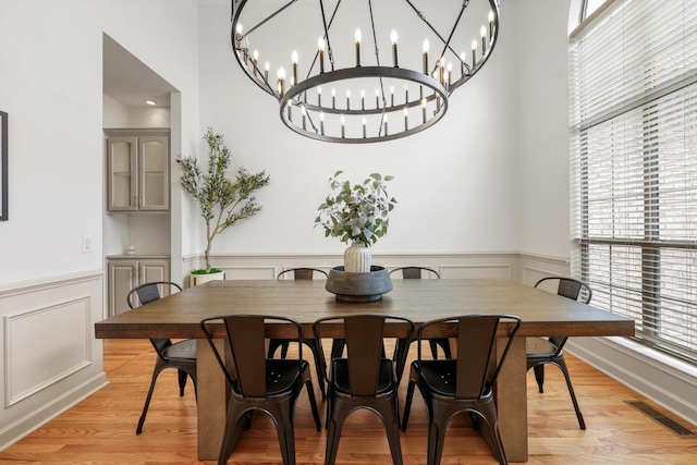 9401 Lazy Circles Dr, Ooltewah, TN 37363 - dining space with a chandelier, a wainscoted wall, light wood-type flooring, and a decorative wall