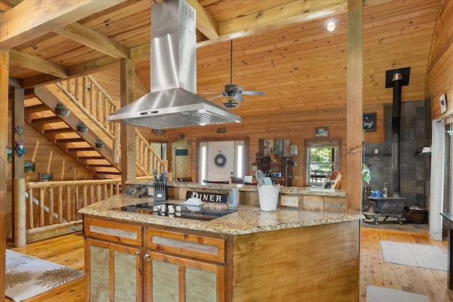 539 Bland Hollow Rd, Hohenwald, TN 38462 - kitchen with extractor fan, a wood stove, wood walls, light wood-style floors, and high vaulted ceiling