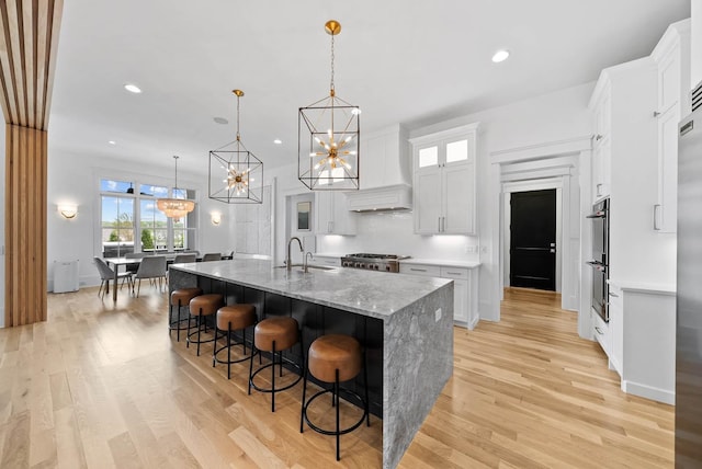 6004 Pelican Way, College Grove, TN 37046 - kitchen with a chandelier, custom exhaust hood, light wood-style floors, white cabinets, and recessed lighting