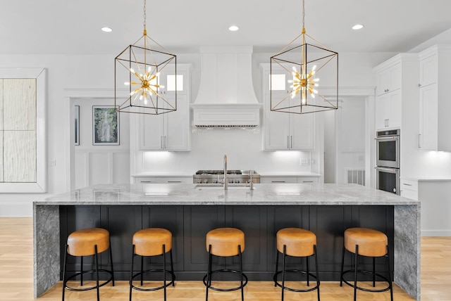 6004 Pelican Way, College Grove, TN 37046 - kitchen featuring custom range hood, a chandelier, stainless steel double oven, light wood finished floors, and white cabinetry