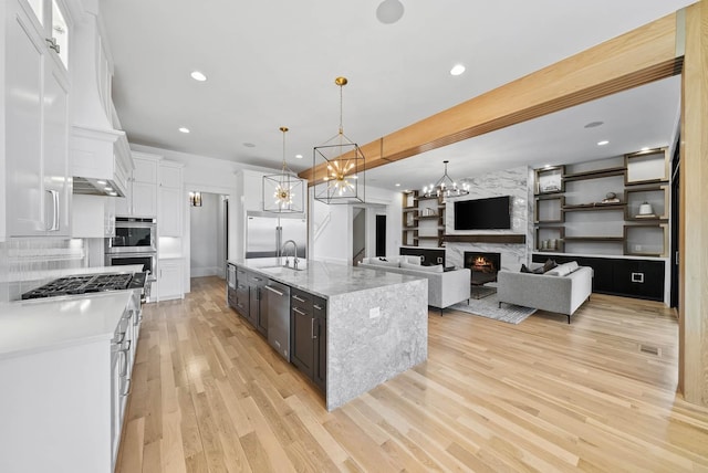 6004 Pelican Way, College Grove, TN 37046 - kitchen featuring appliances with stainless steel finishes, white cabinets, light wood-style floors, a chandelier, and hanging light fixtures