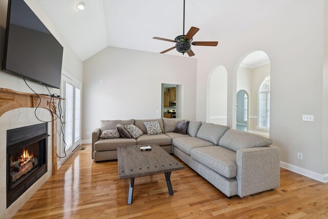 6913 Zion Crossing Ct, Columbia, TN 38401 - living room with a ceiling fan, light wood-style floors, arched walkways, a tiled fireplace, and high vaulted ceiling