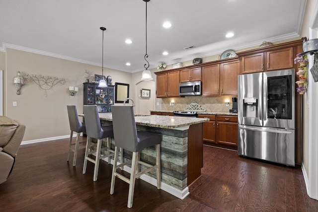7560 Hampstead Hall Dr, Ooltewah, TN 37363 - kitchen with appliances with stainless steel finishes, ornamental molding, brown cabinetry, decorative backsplash, and an island with sink