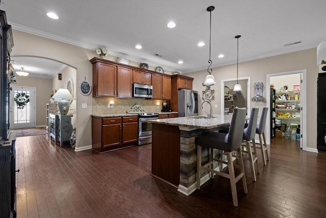 7560 Hampstead Hall Dr, Ooltewah, TN 37363 - kitchen with appliances with stainless steel finishes, arched walkways, ornamental molding, light stone counters, and backsplash