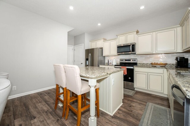 1906 Charismatic Pl, Murfreesboro, TN 37128 - kitchen featuring appliances with stainless steel finishes, cream cabinets, light stone countertops, a center island, and recessed lighting