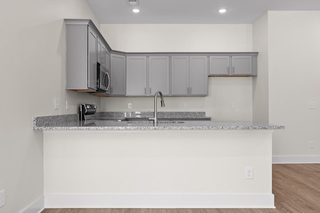 212 Mcbrien Rd, Chattanooga, TN 37411 - kitchen featuring gray cabinets, stainless steel microwave, a peninsula, light stone countertops, and recessed lighting