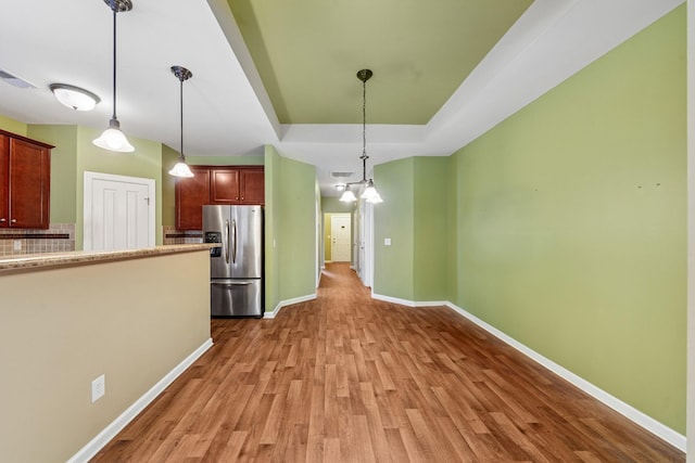 2438 Duxbury Dr, Columbia, TN 38401 - kitchen featuring stainless steel refrigerator with ice dispenser, a raised ceiling, light wood-style flooring, hanging light fixtures, and decorative backsplash