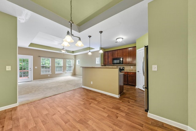 2438 Duxbury Dr, Columbia, TN 38401 - kitchen with black microwave, a tray ceiling, light wood-style floors, and open floor plan