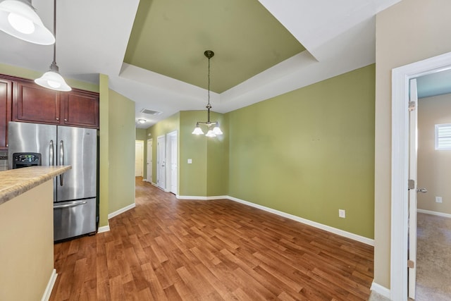2438 Duxbury Dr, Columbia, TN 38401 - kitchen featuring stainless steel fridge with ice dispenser, a raised ceiling, light countertops, light wood finished floors, and decorative light fixtures