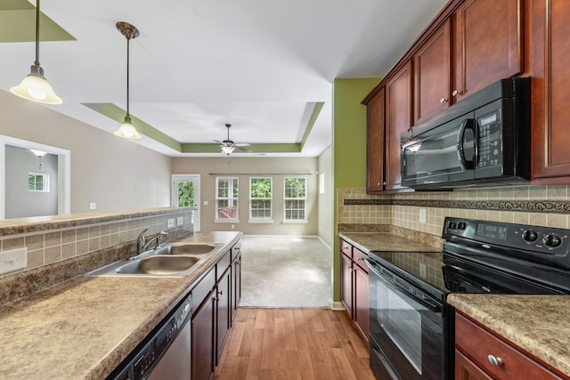 2438 Duxbury Dr, Columbia, TN 38401 - kitchen featuring black appliances, light wood-style floors, hanging light fixtures, a raised ceiling, and decorative backsplash