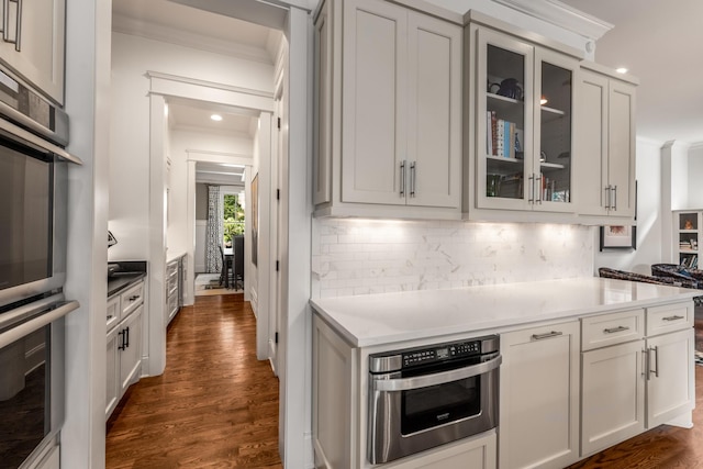 1727 Hillmont Dr, Nashville, TN 37215 - kitchen featuring crown molding, dark wood-style flooring, tasteful backsplash, stainless steel double oven, and glass insert cabinets