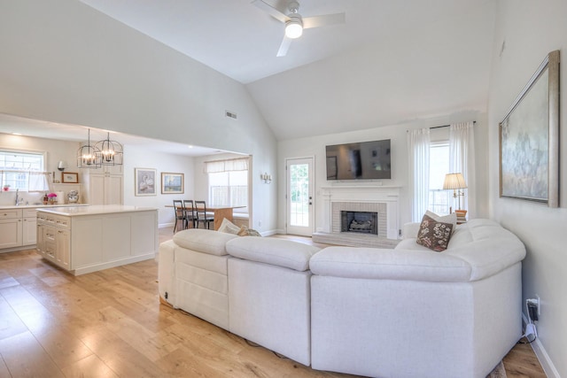 2808 Lafayette Dr, Thompsons Station, TN 37179 - living area with healthy amount of natural light, light wood-style floors, high vaulted ceiling, a brick fireplace, and a ceiling fan