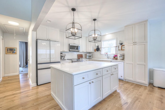 2808 Lafayette Dr, Thompsons Station, TN 37179 - kitchen featuring appliances with stainless steel finishes, white cabinets, light wood finished floors, a kitchen island, and light countertops