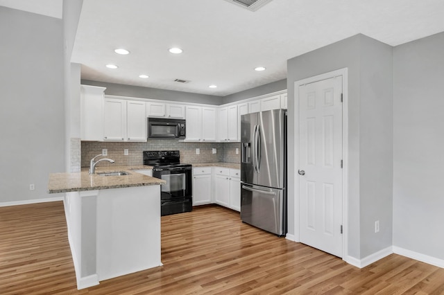 3313 Monoco Dr, Spring Hill, TN 37174 - kitchen with black appliances, a peninsula, light stone counters, white cabinetry, and backsplash