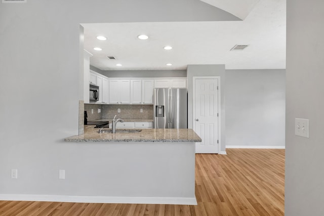 3313 Monoco Dr, Spring Hill, TN 37174 - kitchen with stainless steel refrigerator with ice dispenser, black microwave, white cabinets, a peninsula, and light stone counters