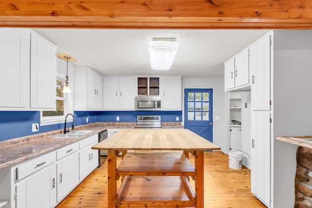 1811 Angel Ln, Signal Mountain, TN 37377 - kitchen with stainless steel appliances, light wood-style flooring, white cabinets, a textured ceiling, and decorative light fixtures