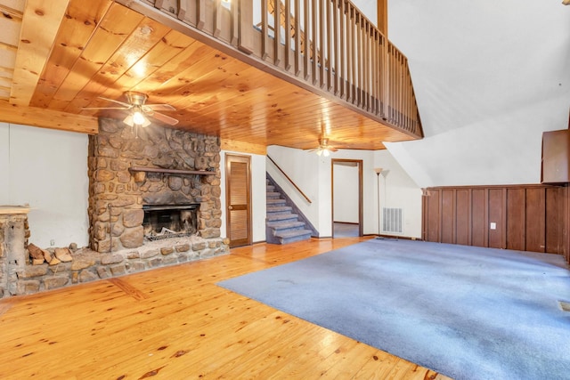 1811 Angel Ln, Signal Mountain, TN 37377 - unfurnished living room featuring a ceiling fan, hardwood / wood-style floors, stairway, a stone fireplace, and wooden walls