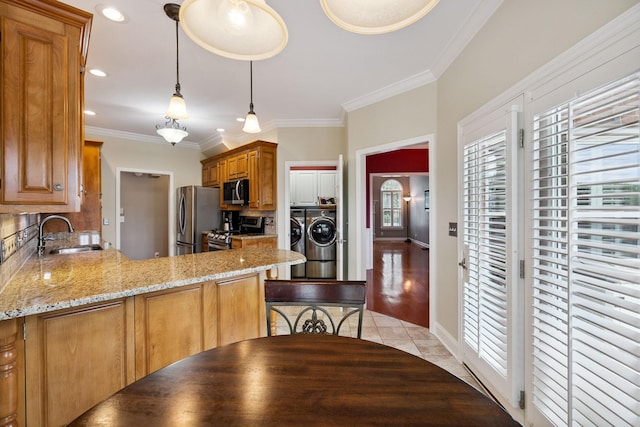 2707 Albany Ct, Murfreesboro, TN 37129 - kitchen with appliances with stainless steel finishes, washer and dryer, backsplash, crown molding, and a peninsula