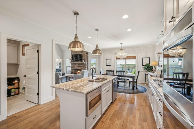 1111 Willow Springs Dr, Lebanon, TN 37087 - kitchen featuring appliances with stainless steel finishes, a chandelier, a stone fireplace, recessed lighting, and a center island with sink