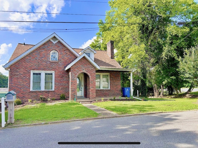 122 W Lake St, Camden, TN 38320 - view of front of house featuring a chimney, brick siding, a shingled roof, and a front lawn
