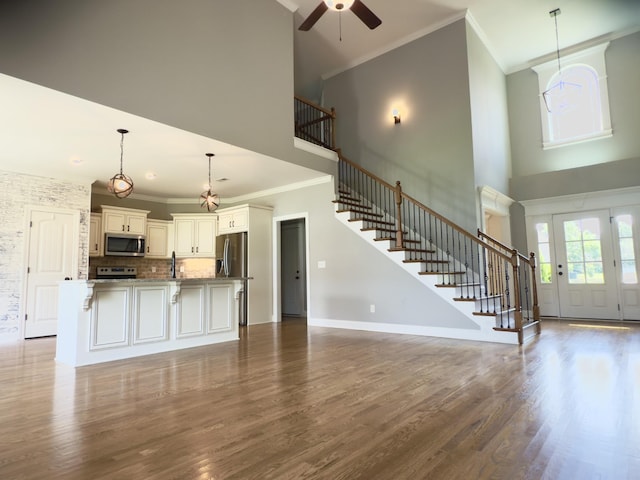 5120 Prickly Pine Pl, Murfreesboro, TN 37129 - unfurnished living room featuring a high ceiling, crown molding, stairs, a ceiling fan, and dark wood-type flooring