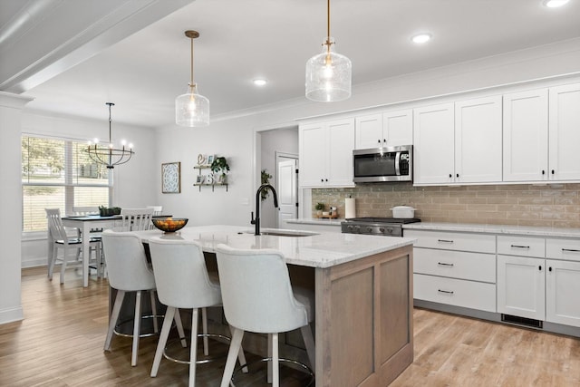 8665 Woodbury Acre Ct, Harrison, TN 37341 - kitchen featuring stainless steel microwave, decorative backsplash, light wood-type flooring, a center island with sink, and recessed lighting