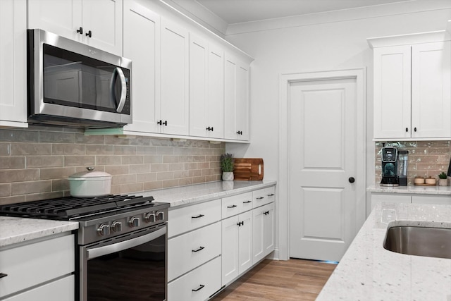 8665 Woodbury Acre Ct, Harrison, TN 37341 - kitchen featuring stainless steel appliances, backsplash, white cabinets, light wood-style flooring, and light stone counters