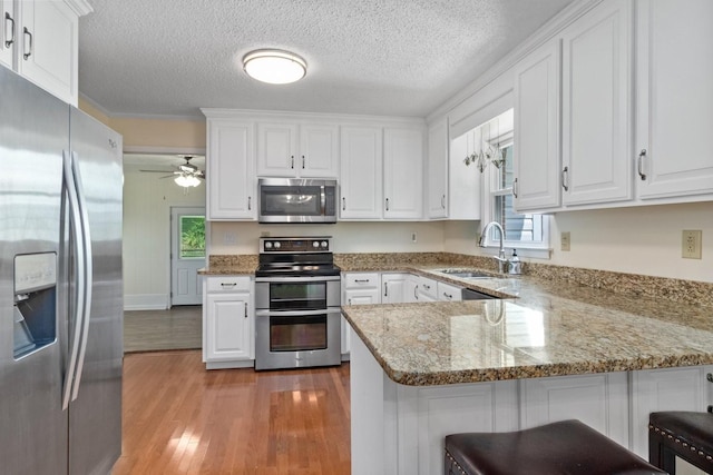 435 Forest St, Lewisburg, TN 37091 - kitchen with stainless steel appliances, a peninsula, light wood-style floors, white cabinets, and a textured ceiling