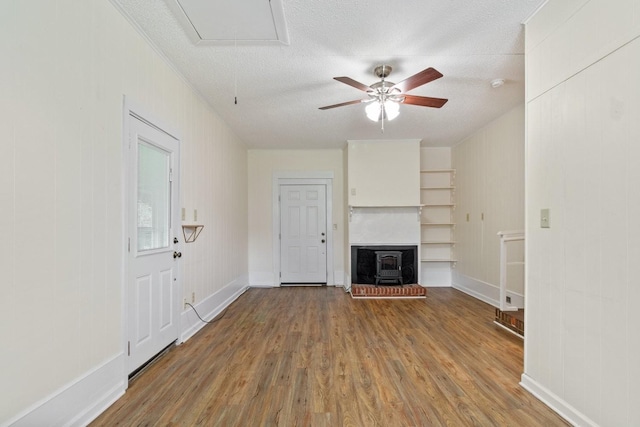435 Forest St, Lewisburg, TN 37091 - unfurnished living room with a wood stove, wood finished floors, a ceiling fan, a textured ceiling, and attic access