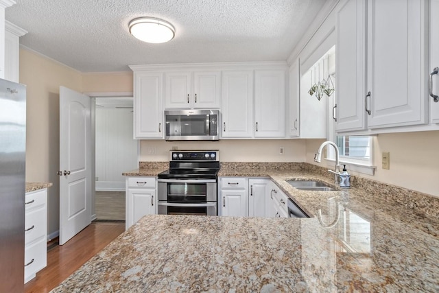 435 Forest St, Lewisburg, TN 37091 - kitchen with appliances with stainless steel finishes, white cabinetry, wood finished floors, light stone countertops, and a textured ceiling