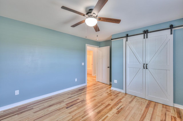 1059 S Cross Bridges Rd, Mount Pleasant, TN 38474 - unfurnished bedroom featuring a barn door, light wood-style floors, and ceiling fan