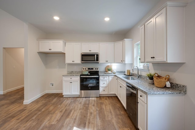766 Billy Wynn Rd, Dickson, TN 37055 - kitchen with stainless steel appliances, light wood-style flooring, white cabinets, light stone counters, and recessed lighting