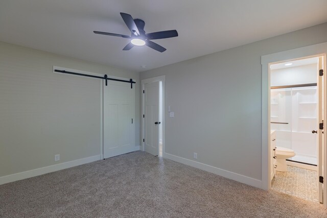 4893 Rainer Dr, Old Hickory, TN 37138 - unfurnished bedroom with a barn door, carpet, connected bathroom, and ceiling fan