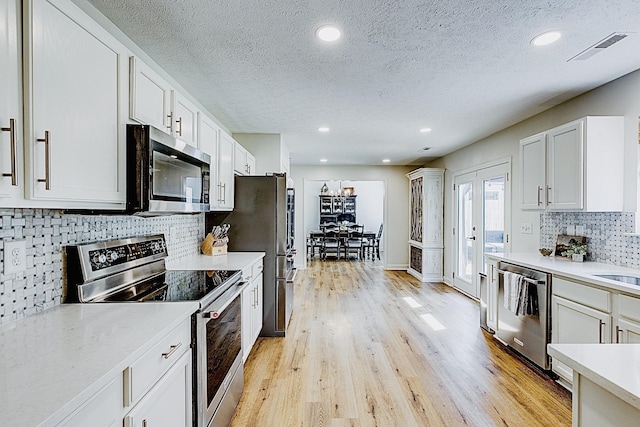 1018 Lowrey Pl, Spring Hill, TN 37174 - kitchen with appliances with stainless steel finishes, light countertops, backsplash, a textured ceiling, and light wood-style flooring