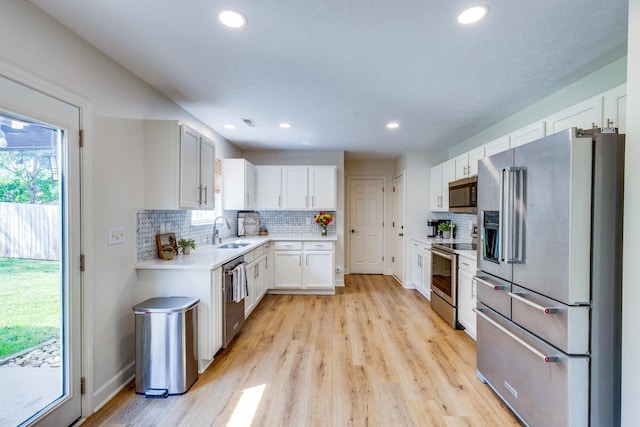 1018 Lowrey Pl, Spring Hill, TN 37174 - kitchen featuring appliances with stainless steel finishes, light countertops, light wood-style flooring, tasteful backsplash, and white cabinetry