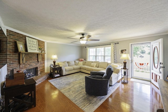 127 Fisherdale Dr, Decaturville, TN 38329 - living area featuring ornamental molding, a textured ceiling, a ceiling fan, wood finished floors, and a brick fireplace