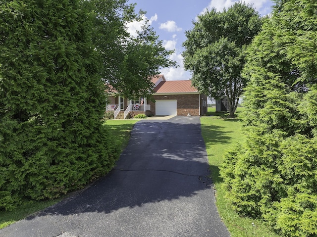 127 Fisherdale Dr, Decaturville, TN 38329 - obstructed view of property with asphalt driveway, an attached garage, a metal roof, a front lawn, and brick siding