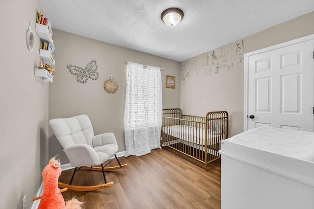 261 Golden Pond Ave, Oak Grove, KY 42262 - bedroom featuring wood finished floors, a crib, and a textured ceiling