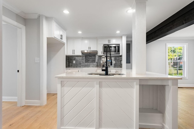 310 E Highland Dr, Columbia, TN 38401 - kitchen featuring stainless steel microwave, under cabinet range hood, tasteful backsplash, crown molding, and light wood finished floors