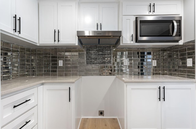 310 E Highland Dr, Columbia, TN 38401 - kitchen featuring stainless steel microwave, white cabinets, under cabinet range hood, and wood finished floors