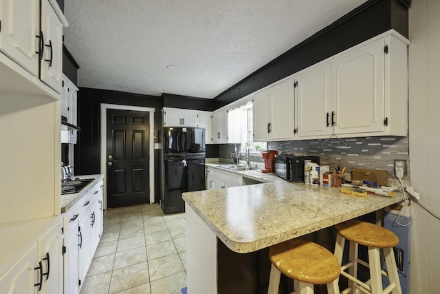 55 Lancaster Ln, Parsons, TN 38363 - kitchen with black appliances, a peninsula, backsplash, light countertops, and white cabinets