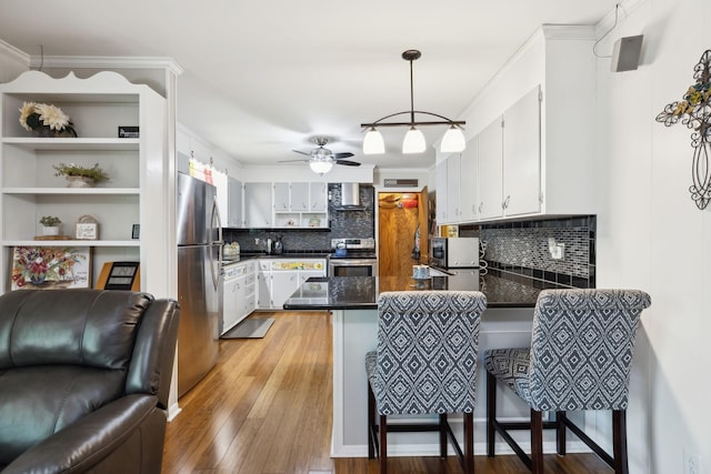 1148 Green Valley Dr, Lewisburg, TN 37091 - kitchen with stainless steel appliances, wall chimney exhaust hood, a peninsula, light wood finished floors, and backsplash