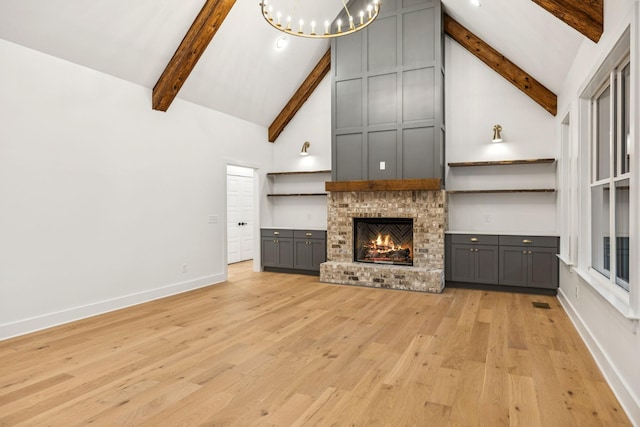 1007 Pheasant Ct, Kingston Springs, TN 37082 - unfurnished living room featuring beamed ceiling, high vaulted ceiling, light wood-style flooring, a brick fireplace, and a chandelier