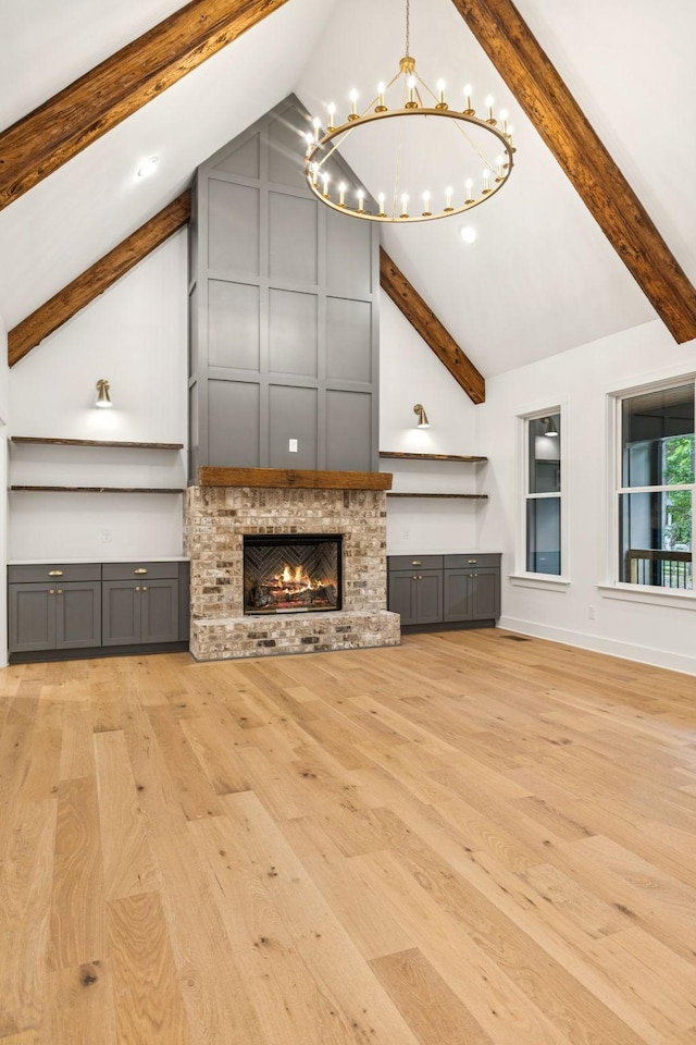 1007 Pheasant Ct, Kingston Springs, TN 37082 - unfurnished living room with a chandelier, light wood-style flooring, beamed ceiling, a brick fireplace, and high vaulted ceiling