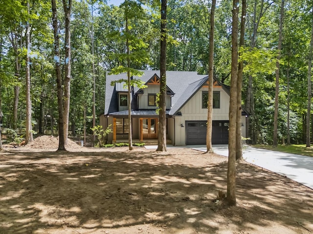 1007 Pheasant Ct, Kingston Springs, TN 37082 - view of front of house featuring concrete driveway, board and batten siding, an attached garage, view of scattered trees, and roof with shingles