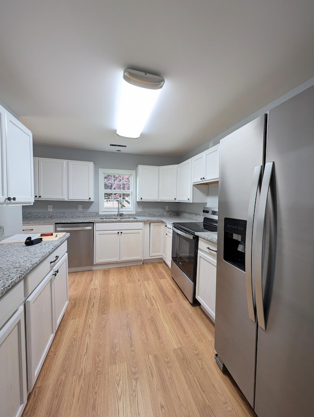 406 Horton St, Decherd, TN 37324 - kitchen with stainless steel appliances, white cabinets, light wood-style floors, and light stone counters