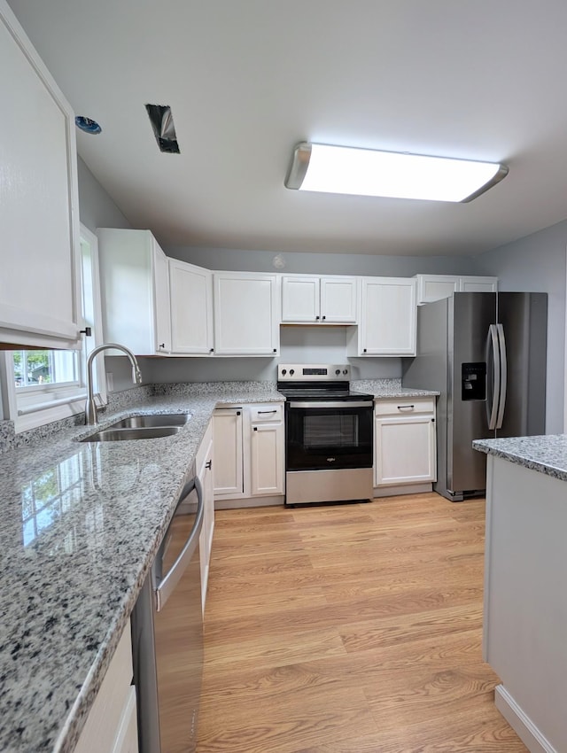 406 Horton St, Decherd, TN 37324 - kitchen featuring appliances with stainless steel finishes, white cabinetry, light stone counters, and light wood-style flooring