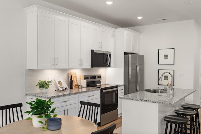 307 Panther Dr, Murfreesboro, TN 37127 - kitchen featuring stainless steel appliances, decorative backsplash, white cabinets, an island with sink, and a kitchen bar