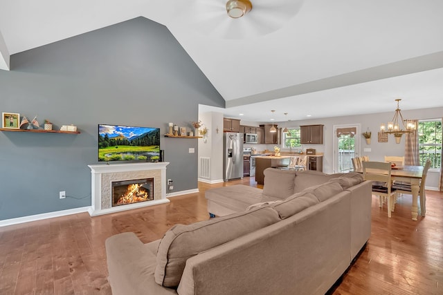 1105 Smiley Troutt Rd, Bethpage, TN 37022 - living room featuring high vaulted ceiling, a chandelier, a warm lit fireplace, light wood-style flooring, and ceiling fan