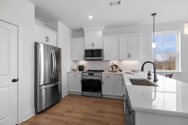 6051 Mill Tree Ct, Nashville, TN 37221 - kitchen featuring appliances with stainless steel finishes, backsplash, white cabinetry, dark wood-type flooring, and hanging light fixtures
